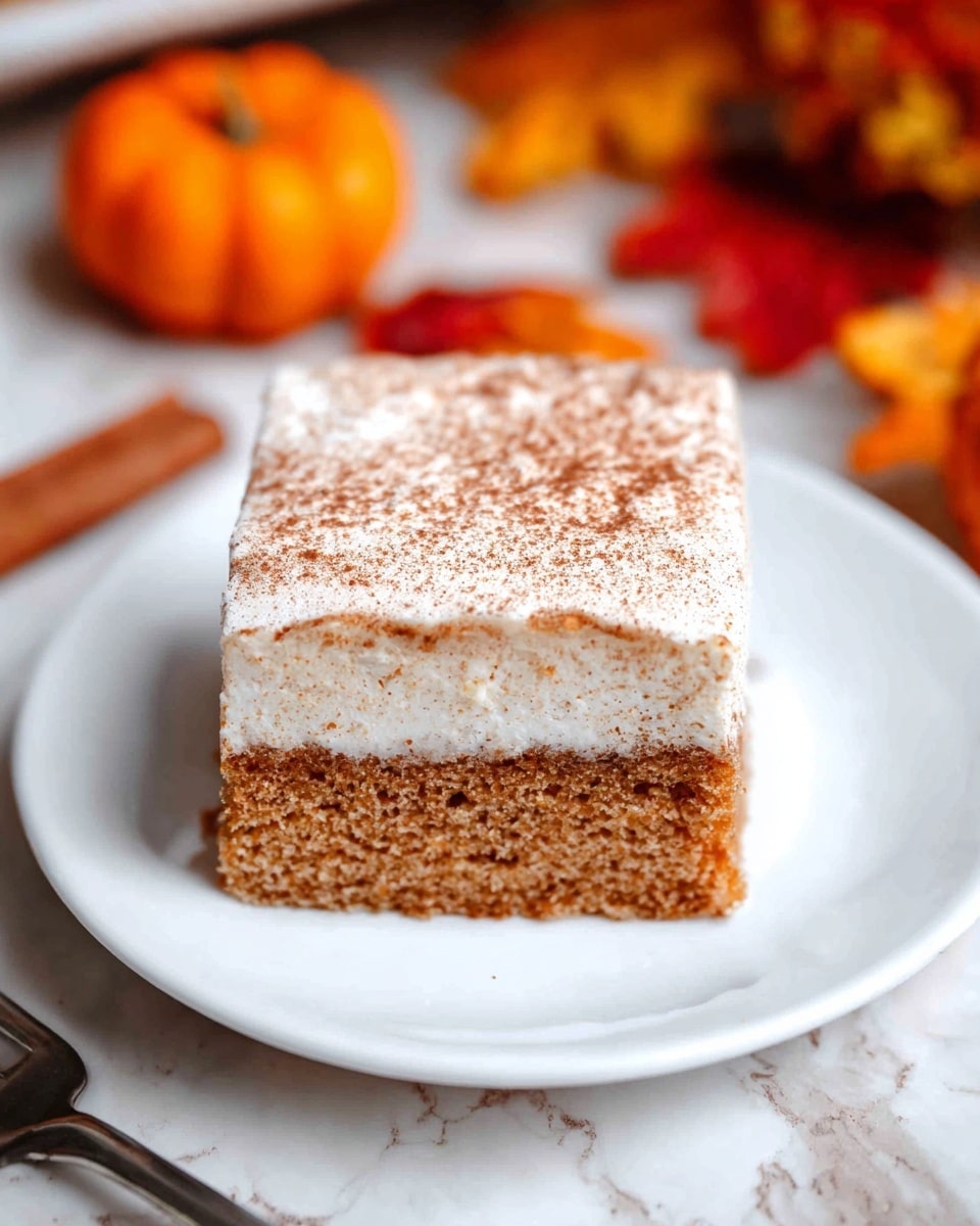 The image shows a square piece of cake with two layers on a white plate. The bottom layer is a thick, moist, golden brown cake with a slightly crumbly texture, while the top layer is a thick, smooth white frosting dusted lightly with a fine brown powder, likely cinnamon. The cake's edges are clean and the top layer is flat and even. A silver fork lies next to the cake on the plate, and the background features a white marbled texture surface with blurred shapes of orange and yellow. photo taken with an iphone --ar 4:5 --v 7