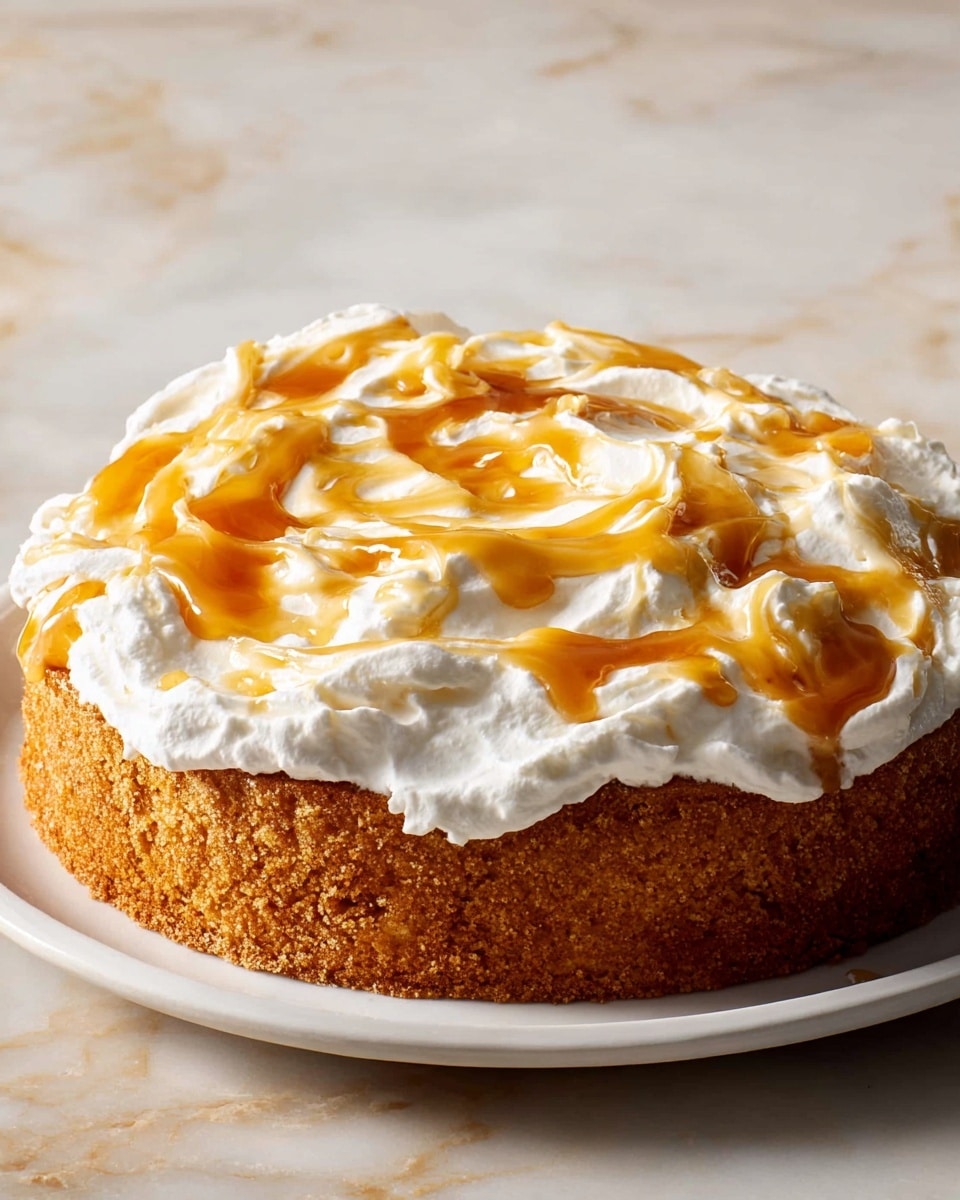 A single-layer, thick golden-brown cake with a rough texture on the side is centered on a white round plate. On top of the cake is a thick spread of smooth white cream, swirled with glossy, golden caramel sauce in large, uneven patches covering the entire surface. The cake and plate sit on a white marbled surface. photo taken with an iphone --ar 4:5 --v 7