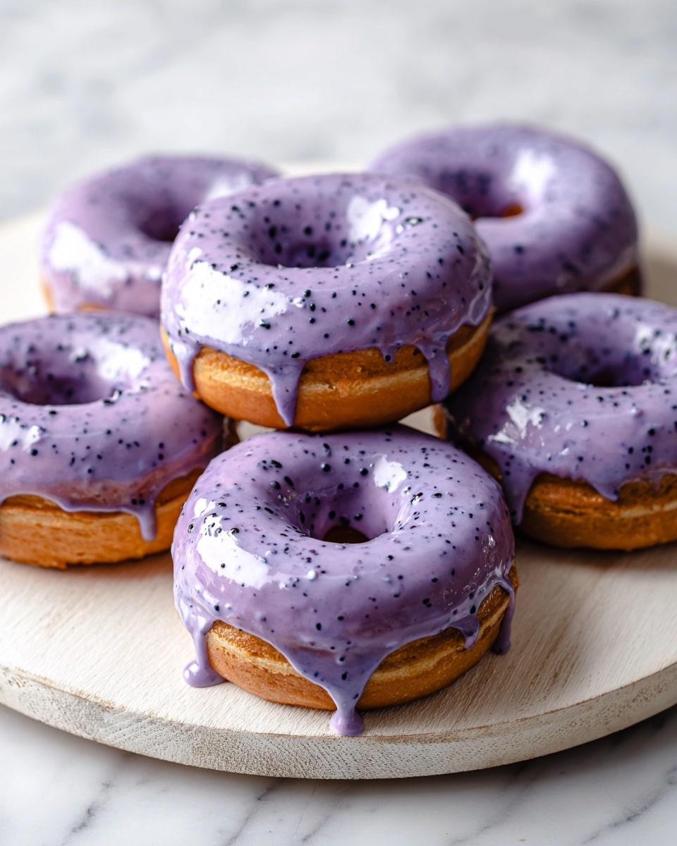 Six small round donuts are shown on a light wooden board over a white marbled surface. Each donut has a smooth, shiny layer of light purple glaze on top that looks creamy and slightly thick, with small darker specks spread through it. The donuts themselves are a darker color but mostly covered by the glaze. The glaze drips slightly over the edges, giving a soft texture that contrasts with the smooth wooden board. photo taken with an iphone --ar 4:5 --v 7