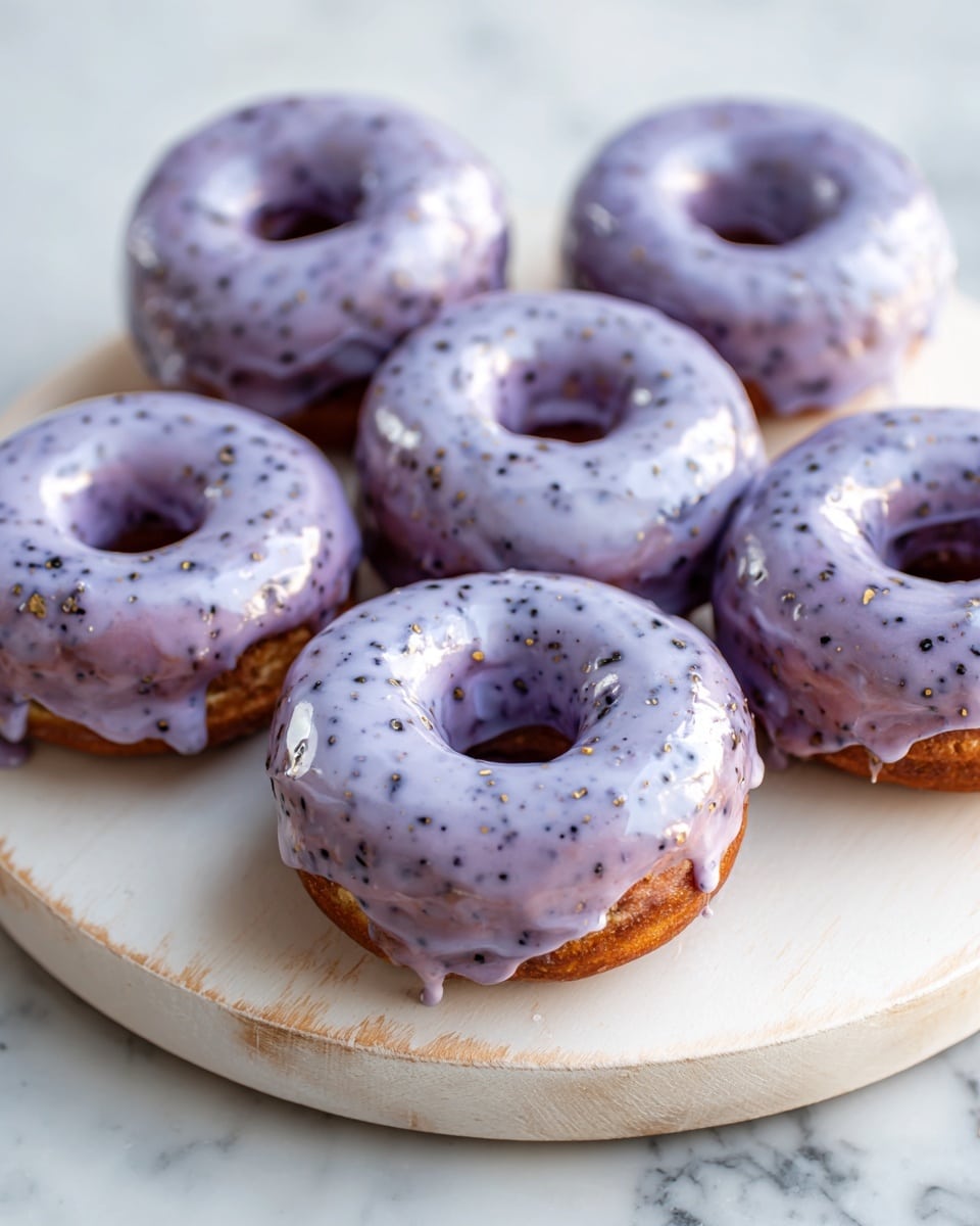 Six donuts are shown on a round white wooden board. Each donut has one layer: a shiny, thick light purple glaze with small dark flecks covering the whole top, dripping unevenly over the edges. The donuts themselves are darker beneath the glaze, with some spots showing through. The white wooden board rests on a white marbled surface. Photo taken with an iphone --ar 4:5 --v 7