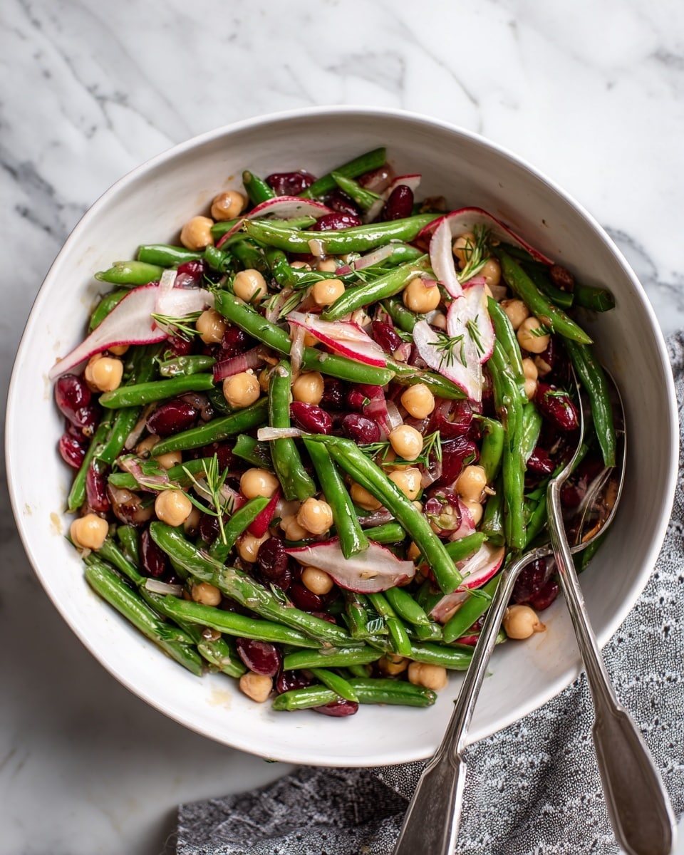 A white bowl filled with a colorful salad shows three main layers: bright green cut green beans, round beige chickpeas, and dark red kidney beans mixed throughout. Thinly sliced round radishes with pink edges and white centers, along with thin shreds of white onion and small green herb bits, are scattered on top. Two silver forks rest on the bowl’s edge, and the bowl is placed on a white marbled surface with a gray patterned cloth nearby. photo taken with an iphone --ar 4:5 --v 7