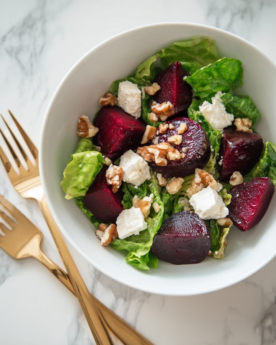 A white bowl is filled with a fresh salad made of three main layers. The bottom layer is green leafy lettuce, with light and dark green tones and some reddish veins, covering the base and sides of the bowl. On top of the greens, rich dark red beet pieces are scattered, cut into thick wedges showing a shiny, slightly wet texture. The top layer has white crumbles of soft cheese and small pieces of chopped brown nuts sprinkled over the salad. The bowl sits on a white marbled surface with a gold fork near the top right corner. Photo taken with an iphone --ar 4:5 --v 7