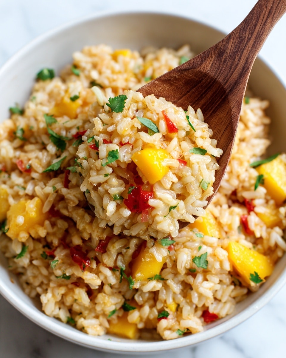 A close-up view of a white bowl filled with a mixed rice dish, showing several colorful layers: fluffy rice grains mixed with small yellow mango chunks, red tomato pieces, and green herbs sprinkled on top. The texture looks moist and soft with some rice grains sticking to a wooden spoon, which a woman's hand is holding from the side. The background features a clean, white marbled surface that contrasts with the vibrant food colors. photo taken with an iphone --ar 4:5 --v 7
