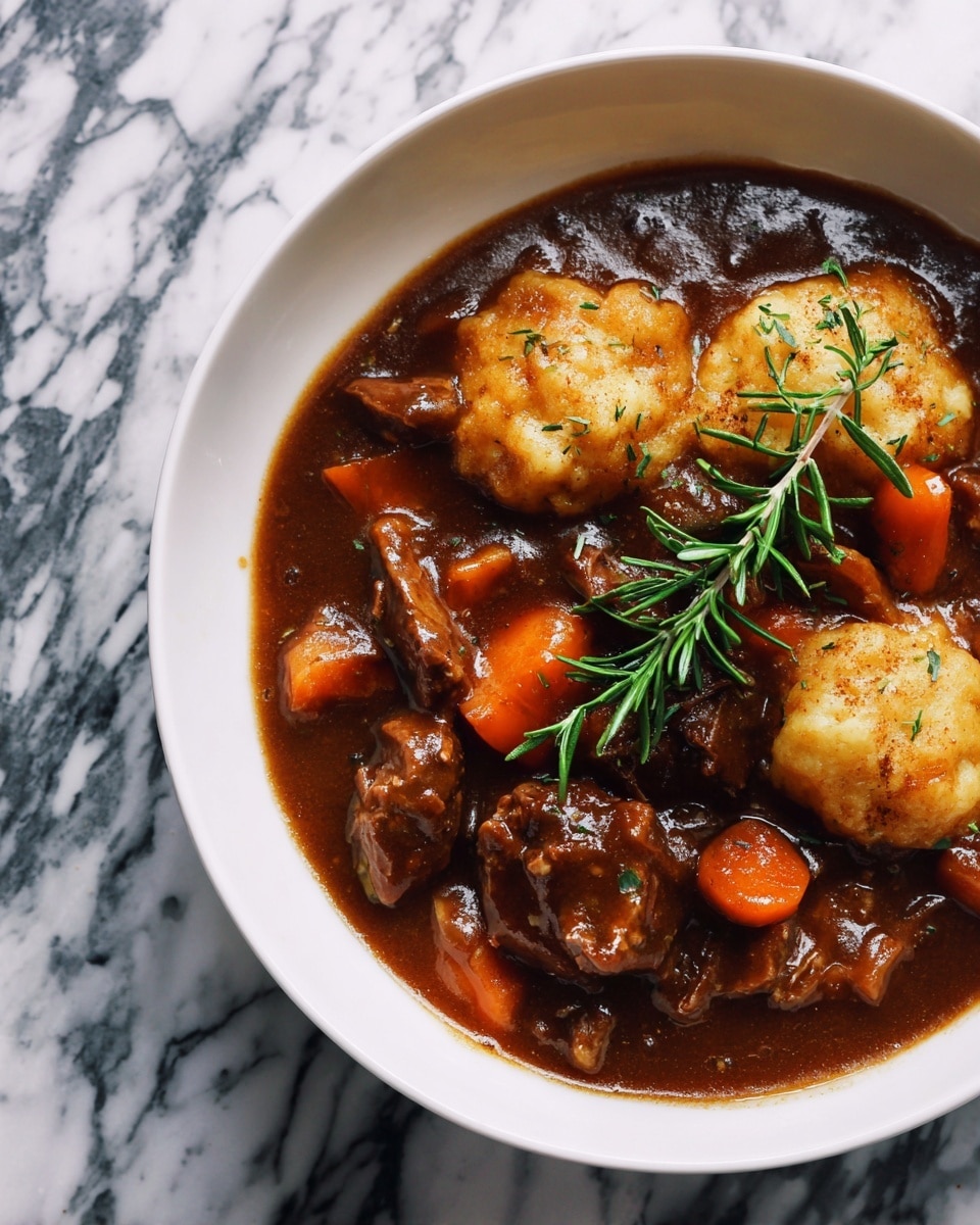 A white bowl filled with rich brown stew containing tender chunks of meat and orange carrot slices, topped with two golden dumplings with a slightly rough texture and a sprig of green rosemary placed on top, all sitting on a white marbled surface. photo taken with an iphone --ar 4:5 --v 7
