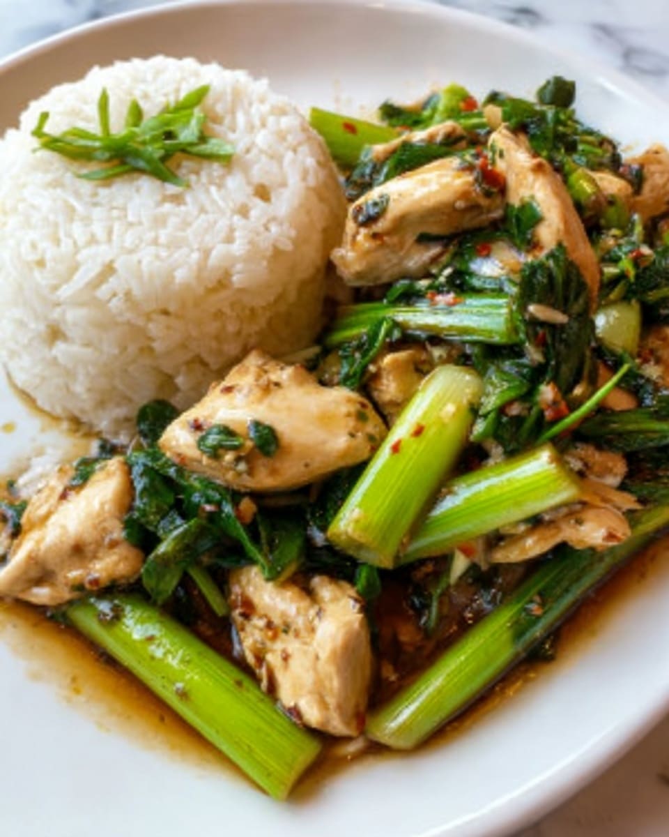 The image shows a close-up of a white plate with two main parts. On the left side, there is a neat round mound of white rice with a few green herbs on top. On the right side, there is a mix of cooked chicken pieces that are light brown and tender, combined with bright green leafy vegetables and long green stalks. The food looks shiny with a brown sauce that covers the chicken and vegetables, giving a fresh and tasty look. The plate is set on a white marbled surface. photo taken with an iphone --ar 4:5 --v 7